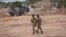 FILE - Burkina Faso army officers patrol near a French armored vehicle parked in Kaya, capital of Burkina Faso's north-central region, after people protested the passage of a large French army convoy in transit to neighboring Niger, Nov. 20, 2021. 