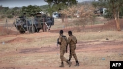 Des officiers de l'armée burkinabè patrouillent près d'un véhicule blindé français stationné à Kaya, capitale de la région du centre-nord du Burkina Faso, après que des personnes ont protesté contre le passage d'un grand convoi logistique de l'armée française.