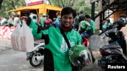 A Go-Jek driver shows boxes with food for his customer in front of a food stall in Jakarta, Indonesia, July 13, 2017. 