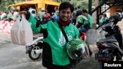 A Go-Jek driver shows boxes with food for his customer in front of a food stall in Jakarta, Indonesia, July 13, 2017. 