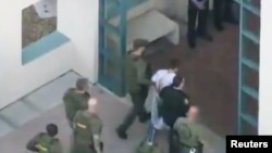 Police escort a suspect into the Broward Jail after checking him at the hospital following a shooting incident at Marjory Stoneman Douglas High School in Parkland, Florida, Feb. 14, 2018 in a still image taken from a video.