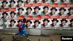 A schoolgirl walks past campaign posters in support of Nigeria's President Goodluck Jonathan along a road in Ikoyi district in Lagos, Feb. 13, 2015. 