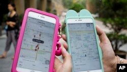 Women holding their smartphones show the ride-hailing apps Uber Technology Ltd., left, and Didi Chuxing at a residential compound in Beijing, Aug. 1, 2016. 