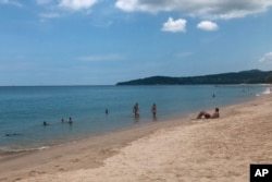 FILE - In this March 26, 2020, photo, tourists swim on a beach, Phuket, Thailand.