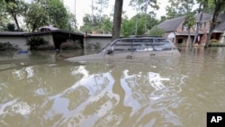 FILE - A car is submerged in floodwaters in the aftermath of Hurricane Harvey near the Addicks and Barker Reservoirs in Houston, Sept. 4, 2017. 