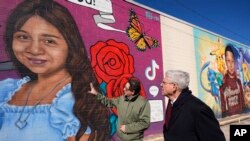 Seniman Abel Ortiz (kiri) menjelaskan mural yang dibuat untuk para korban penembakan di sekolah di Texas kepada Jaksa Agung AS Merrick Garland dalam kunjungan Garland ke Uvalde, Texas, pada 17 Januari 2024. (Foto: AP/Eric Gay)