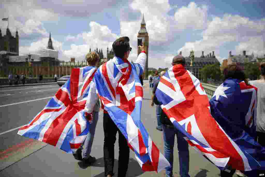 Warga berjubah bendera Inggris berjalan menuju Menara Big Ben dan Gedung Parlemen di London (26/6). (AFP/Odd Andersen)