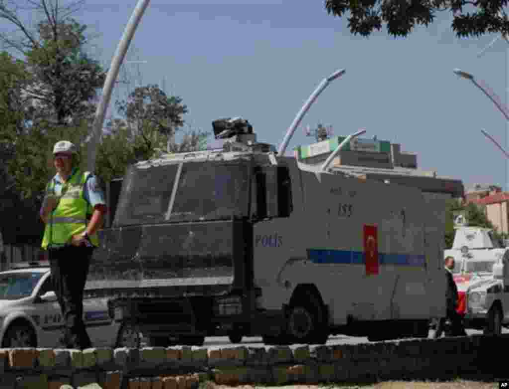 A police officer stands next to riot police vehicles outside the Kugulu Park in Ankara, Turkey, Tuesday, June 18, 2013. After weeks of confrontation with police, sometimes violent, Turkish protesters are using a new form of resistance: standing silently. 