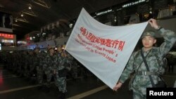 Members of a medical aid team of People's Liberation Army (PLA) carry a flag during their departure ceremony at Beijing Capital International Airport, in Beijing as more than 200 soldiers from a military hospital departed for Africa to help fight Ebola, Nov. 14, 2014. 