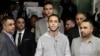 Ali Hassan, center, speaks at a news conference after his wife, Shaima Swileh, hidden, arrived at San Francisco's airport, Dec. 19, 2018. Swileh is the Yemeni mother who was given a travel ban waiver so she could come to California to see her dying 2-year-old son.