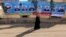 FILE - A woman walks past a campaign banner for the Nour party ahead of parliamentary elections, in Cairo, November 27, 2011.