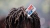 A supporter of former Haitian President Jean-Bertrand Aristide looks into the camera as he waits with others near the airport for his expected arrival from Cuba, where he underwent medical treatment, in Port-au-Prince, July 16, 2021. 