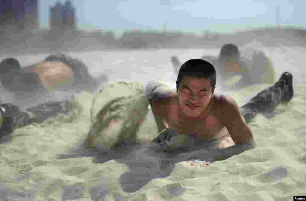 A paramilitary policeman crawls with his comrades in the sand during heat endurance training in Hefei, Anhui province, China. The temperature in Hefei reached 39 degrees Celsius (102.2 degrees Fahrenheit).