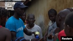 FILE - A UNICEF worker shares information on Ebola and how to help prevent its spread in Conakry, Guinea in this UNICEF handout photo.