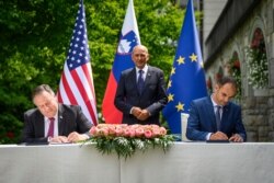 U.S. Secretary of State Mike Pompeo, left, and Slovenia's Foreign Minister Anze Logar sign an agreement on 5G internet technology as Slovenia's Prime Minister Janez Jansa stands at center, in Bled, Slovenia, Aug. 13, 2020.