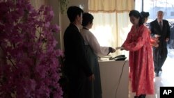 A woman receives a ballot to vote to elect deputies to the 13th Supreme People's Assembly in Pyongyang, North Korea, March 9, 2014.