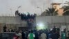 Para pengunjuk rasa memanjat tembok di Kedutaan Besar Swedia di Baghdad Kamis, 20 Juli 2023. Para pengunjuk rasa yang marah dengan rencana pembakaran salinan Al-Qur'an menyerbu kedutaan pada Kamis pagi, membobol kompleks dan menyalakan api kecil. (Foto: AP/Ali Jabar)