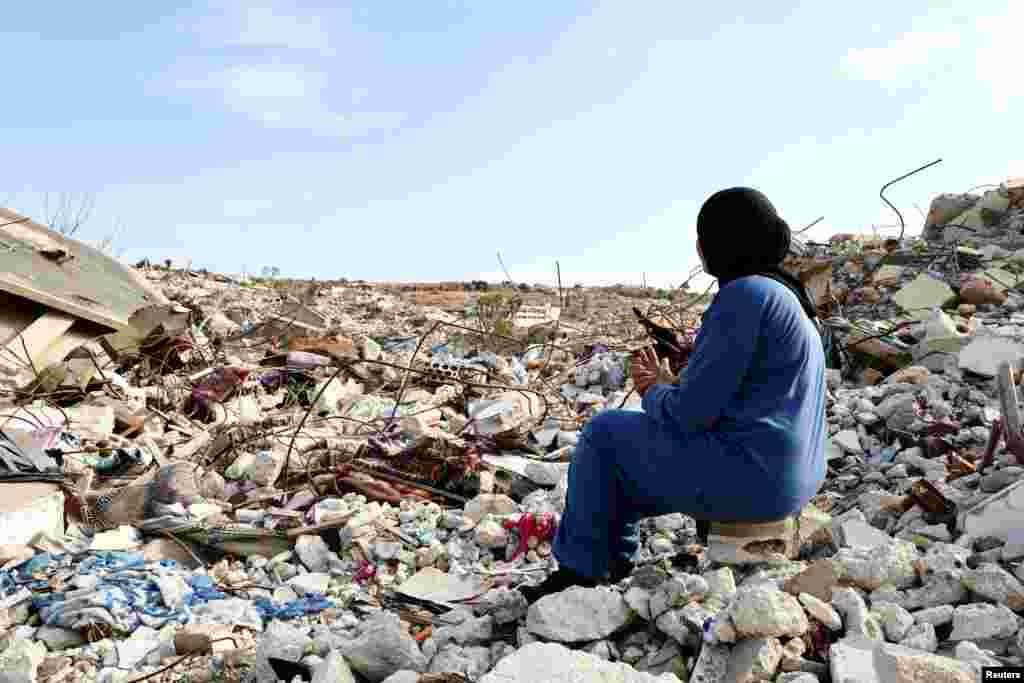 Lebanese woman Manar Feres, who returned to Kfar Kila following Israeli troop withdrawal, sits on the rubble of her damaged home, in Kfar Kila near the border with Israel, Lebanon, Feb.18, 2025. 