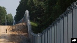 ARCHIVO - Un guardia fronterizo polaco vigila una zona de la frontera entre Polonia y Bielorrusia, cerca de Kuznice, Polonia, el 30 de junio de 2022.