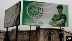 FILE - A man walks by posters of Syrian President Bashar al-Assad that in Arabic read "Homeland, honor, fidelity. Together we will build it," in Aleppo, Syria, Dec. 5, 2016.