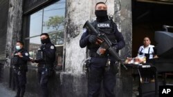 Policías con armas largas custodian las calles después de que el Congreso de El Salvador aprobara el estado de emergencia solicitado por el presidente Nayib Bukele, en medio de una ola de asesinatos relacionados con pandillas, en el centro de San Salvador, el 27 de marzo de 2022.