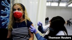 FILE - A woman receives a vaccination against COVID-19 at a temporary health care center at a basketball court in Petah Tikva, Israel, Jan. 28, 2021. 