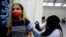 FILE - A woman receives a vaccination against COVID-19 at a temporary health care center at a basketball court in Petah Tikva, Israel, Jan. 28, 2021. 
