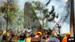 Rescue workers arrive as smoke billows from the wreckage of a Philippine Airforce C-130 transport plane after it crashed in Jolo town, Sulu province on the southern island of Mindanao, July 4, 2021. (Philippine Military Joint Task Force-Sulu)