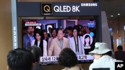 Personas observan una pantalla en la que se muestra una foto del difunto líder de Samsung, Lee Kun Hee, junto a sus hijas. [Foto de archivo]