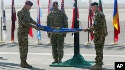 El comandante Joseph Anderson (izquierda) dobla la bandera de la coalición extranjera en Afganistan, luego de arriar su bandera para poner fin a la misión de combate en ese país.