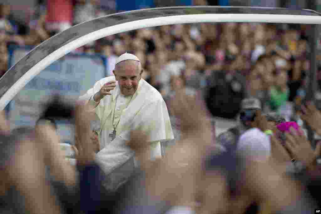 Paus Francis menyapa orang-orang di kendaraannya di wilayah Gloria dalam perjalanannya menuju Istana Uskup Agung di Rio de Janeiro, Brazil.