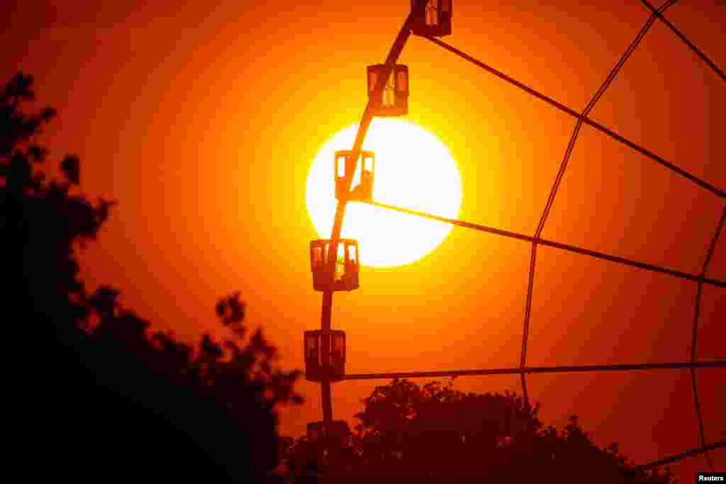 The sun is seen through the giant Ferris wheel at Place de la Concorde at sunset in Paris, France, May 8, 2018.