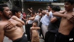 FILE - A Shi'ite Muslim boy beats his chest with others during a Muharram procession, in Lahore, Pakistan.