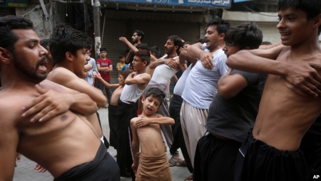 FILE - A Shi'ite Muslim boy beats his chest with others during a Muharram procession, in Lahore, Pakistan.
