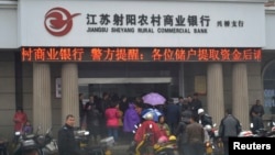 People gather in front of a branch of Jiangsu Sheyang Rural Commercial Bank, in Yancheng, Jiangsu province, March 25, 2014.