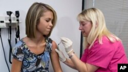 FILE - Lauren Fant, left, 18, braces for a shot of the HPV vaccine administered by nurse Stephanie Pearson in Marietta, Georgia, Dec. 18, 2007.