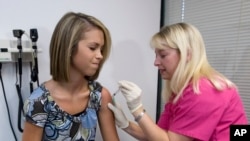 FILE - Lauren Fant, left, 18, braces for a shot of the HPV vaccine administered by nurse Stephanie Pearson in Marietta, Georgia, Dec. 18, 2007.