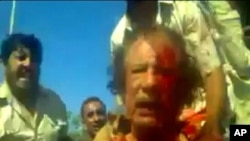 Image taken from amateur video posted on a social media website and obtained by Reuters, October 21, 2011, shows former Libyan leader Moammar Gadhafi, covered in blood, after his capture by NTC fighters in Sirte.