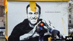圣彼得堡的一个工人正在用颜料覆盖俄罗斯反对派领导人纳瓦尔尼的画像，画像旁的俄文是“新时代的英雄”。（2021年4月28日）