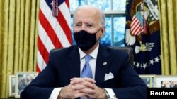 Tổng thống Hoa Kỳ Joe Biden ký lệnh hành pháp tại Phòng Bầu dục của Nhà Trắng ở Washington, sau khi ông nhậm chức tổng thống thứ 46 của Hoa Kỳ, ngày 20 tháng 1 năm 2021.