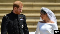 Britain's Prince Harry, Duke of Sussex and his wife Meghan, Duchess of Sussex, leave from the West Door of St George's Chapel, Windsor Castle, in Windsor, on May 19, 2018, after their wedding ceremony. 