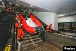 Rescue workers enter a subway station of Metro Line 5 to inspect the floodwaters following heavy rainfall in Zhengzhou, Henan province, China, July 26, 2021. (China Daily via Reuters)