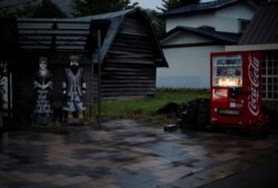 Wooden statues of an Ainu couple stand in front of an Ainu craft shop in the Nibutani district where several Ainu craft shops and a museum are located, in Biratori, Hokkaido Prefecture, Japan, Aug. 23, 2019.