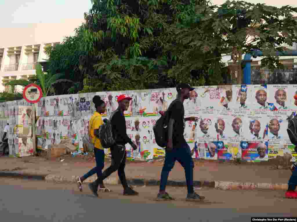 Pessoas passeiam pelas ruas cujos muros t&#234;m cartazes de campanha colados. 21 Novembro 2019