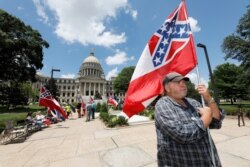 Supporters of the current Mississippi state flag stand outside the state Capitol in Jackson, Mississippi, June 28, 2020.
