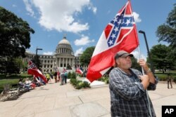 Supporters of the current Mississippi state flag stand outside the state Capitol in Jackson, Mississippi, June 28, 2020.