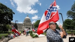 Supporters of the current Mississippi state flag stand outside the state Capitol in Jackson, Mississippi, June 28, 2020.