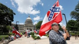 Supporters of the current Mississippi state flag stand outside the state Capitol in Jackson, Mississippi, June 28, 2020.