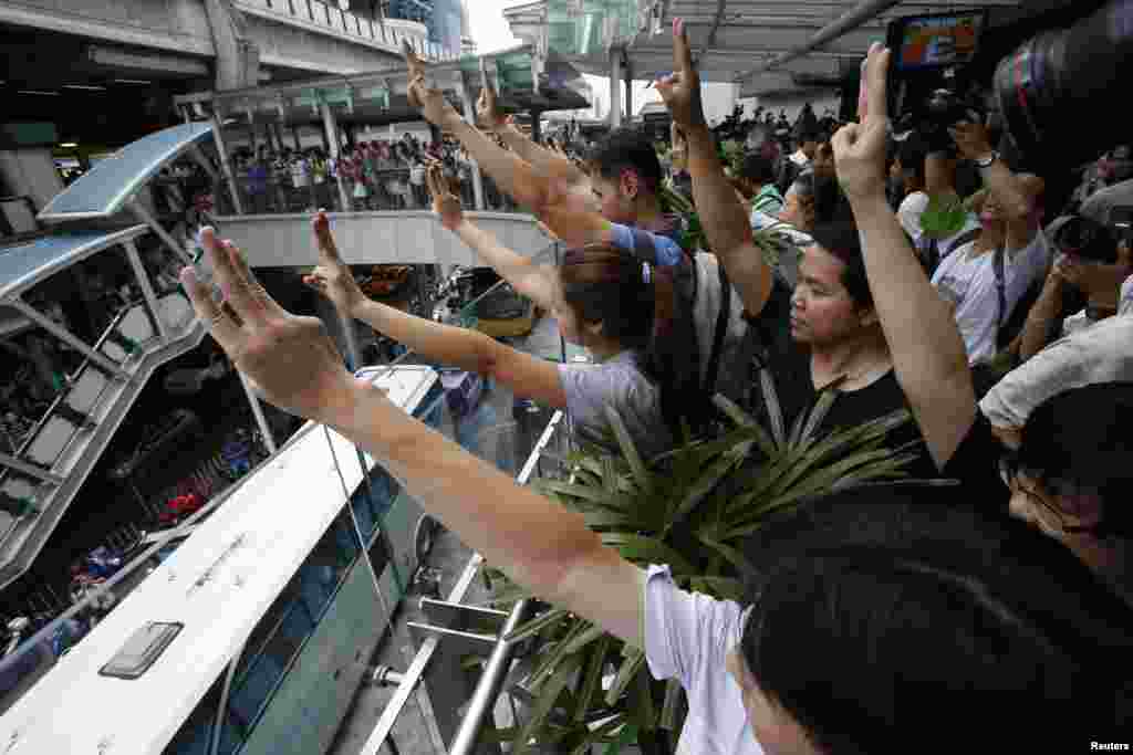 Para demonstran yang melawan kekuasaan militer mengangkat tiga jari tengah tanda pembangkangan dalam demonstrasi singkat di sebuah pusat perbelanjaan di Bangkok (1/6).