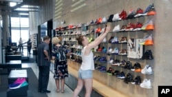 FILE - Shoppers look at shoes at the Nike Miami store on the Lincoln Road Mall in Miami Beach, Fla., Sept 4, 2018. The sneaker seller will launch a foot-scanning tool on its app this summer that will measure and remember the length, width and other dimensions of customers' feet.